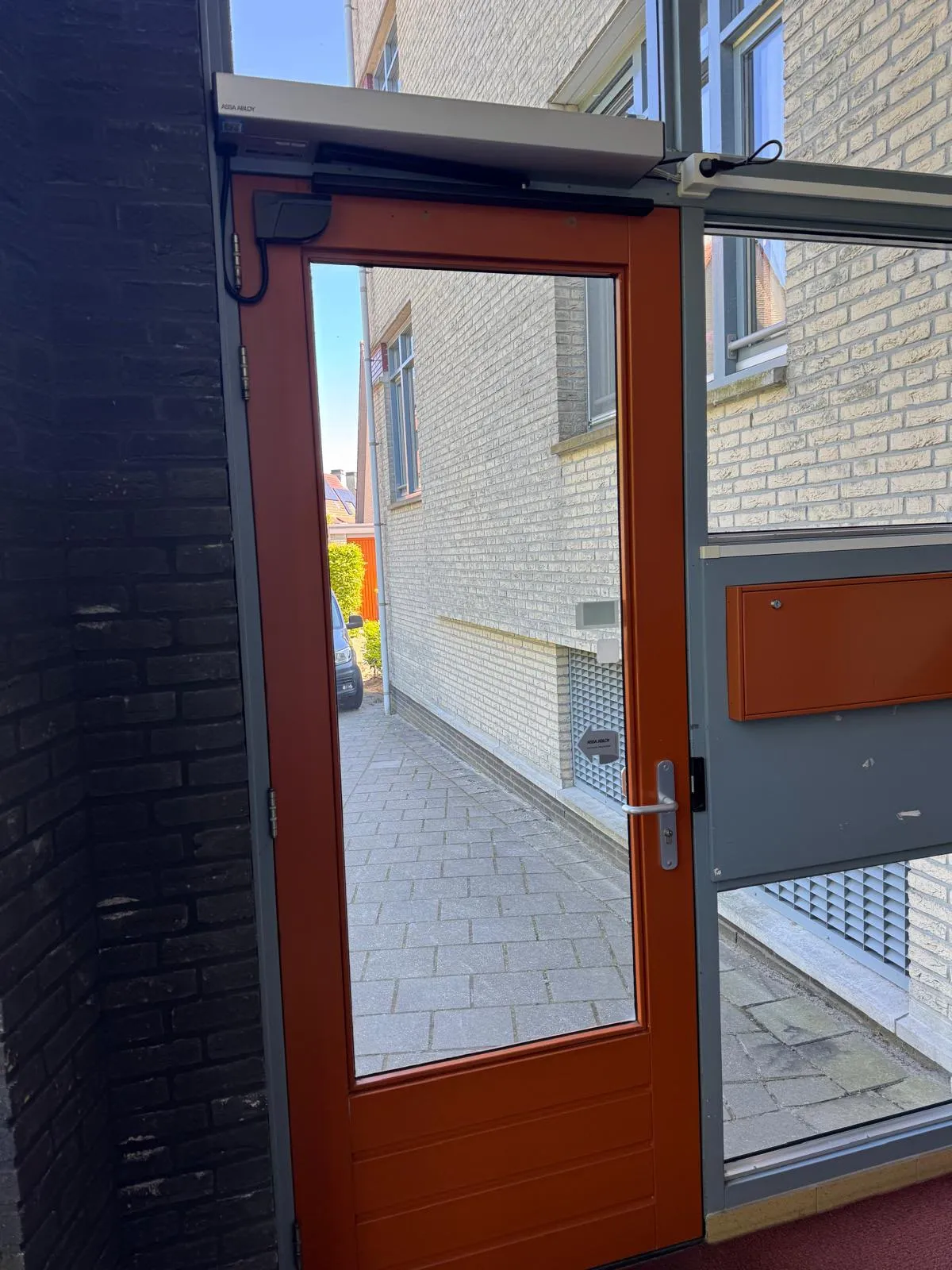 Hoofdentree van een appartementencomplex met draaideurautomaat op het kozijn