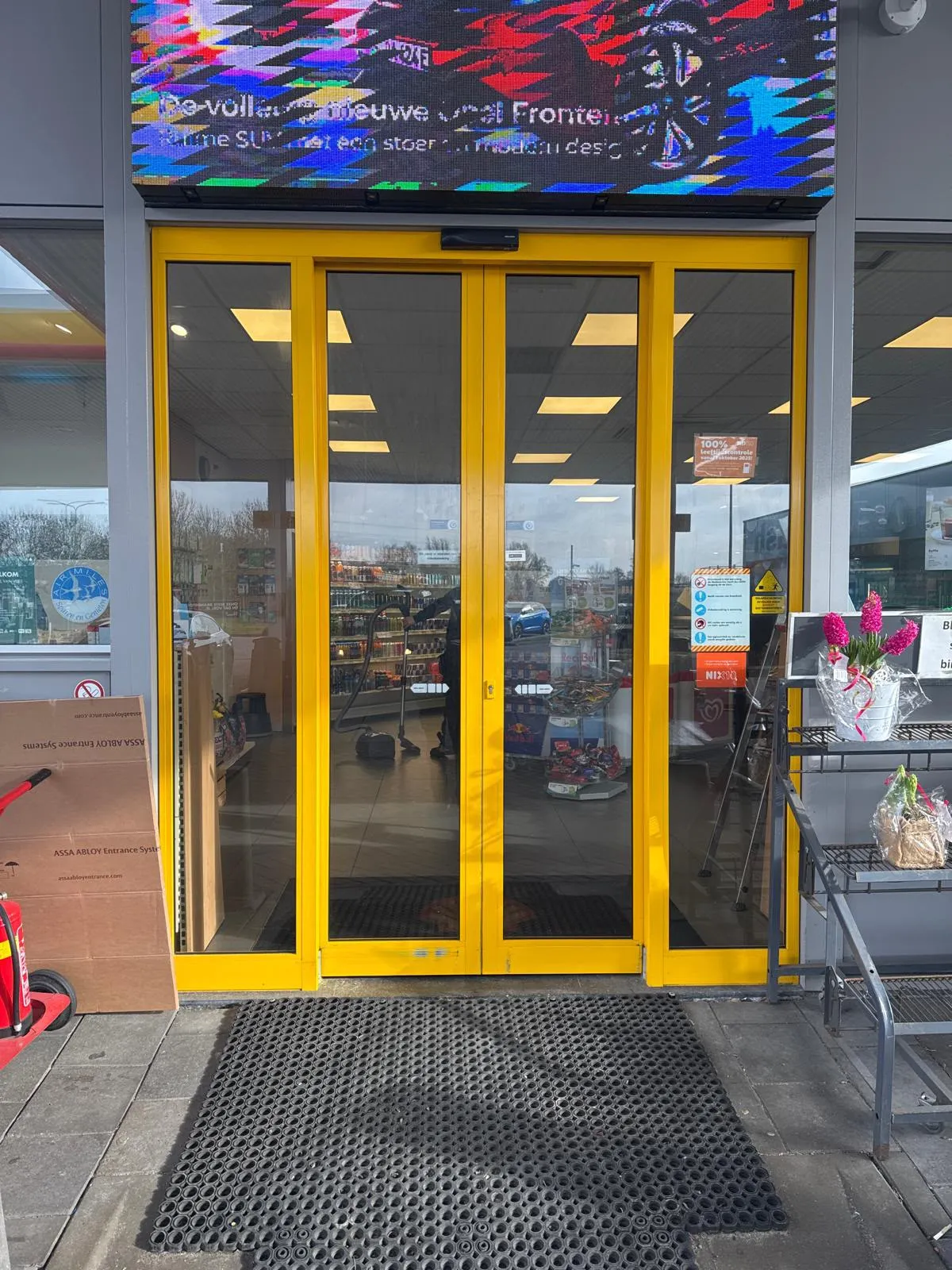 Telescopische schuifdeur in geel bij de entree van een Shell-tankstationshop